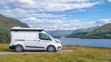 white camper van parked by serene lakeside, surrounded by lush green hills and clear blue sky photo