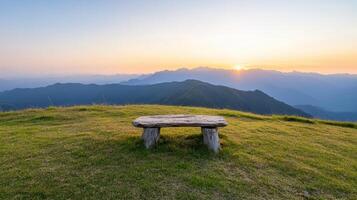 A bench sits on top of a hill overlooking the mountains photo