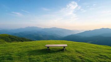 A bench on a grassy hill overlooking the mountains photo