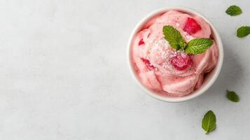 A bowl of strawberry ice cream with mint leaves photo