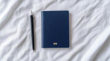 A blue notebook and pen on a bed photo