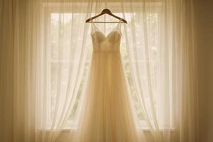 Elegant Wedding Dress Hanging Near Window With Sheer Curtains During Soft Morning Light photo