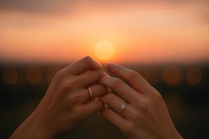 Romantic Sunset Engagement With Intertwined Hands and Rings in the Background photo