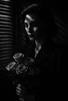 Woman Holding Roses in Low-Light Setting With Shadows Creating Dramatic Effect photo