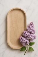Wooden Tray With Lilac Flowers Arranged on Marble Surface photo