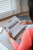 Professional woman reviewing sales data on a clipboard with bar graphs, highlighting business growth and analysis. photo