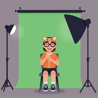 A cheerful child wearing a playful animal hat sits on a chair in a photography studio, surrounded by bright lights in a flat illustration vector