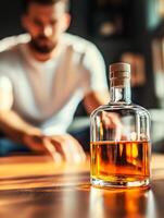 A man sitting at a table with a bottle of whiskey photo