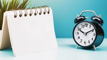 Alarm clock and notepad on blue table photo