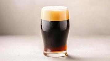 A tall glass of dark beer on a table photo