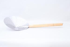 Shiny metallic skimmer with wooden handle, tool for straining and cooking photo