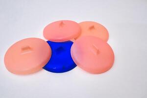 Round Plastic Lids in Varied Colors Arranged Against Bright White Backdrop photo