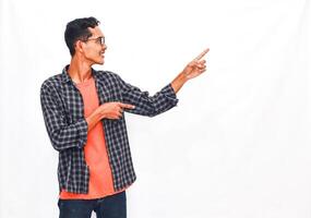 Young Person In Colorful Top And Checked Shirt Pointing Enthusiastically Against Plain Background photo