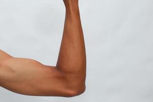 Close Up Of A Flexed Muscular Arm With Dark Brown Skin Against A Light Gray Background photo