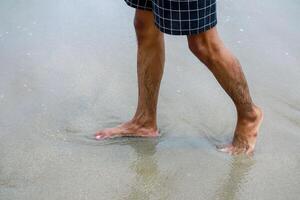 Man strolling along sandy beach enjoying waves and freedom in swimwear photo