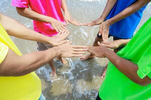 Unity circle of diverse hands on a vibrant beach, demonstrating friendship photo