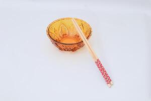 Amber bowl with intricate pattern and a pair of wooden chopsticks with decoration photo