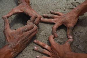 Hands Covered in Sand Creating Geometric Shapes on a Beach Surface photo