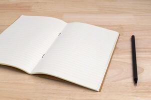 open notebook with pencil on wooden table for mockup blank template photo