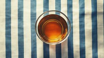 A glass of whiskey on a blue and white striped tablecloth photo
