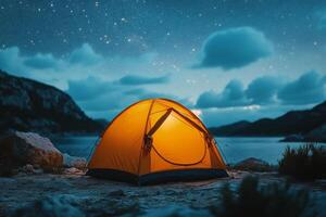A tent is lit up at night in front of a lake photo