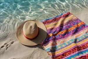 A hat and a towel on the beach with water photo