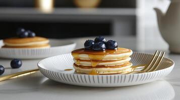A stack of pancakes with syrup and blueberries on a white plate photo