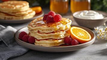 Stack of pancakes with fresh raspberries and orange slices photo