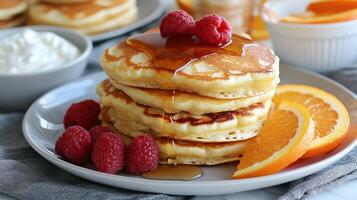 A stack of pancakes with fresh raspberries and orange slices photo
