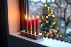 Three red candles sit on a window sill photo