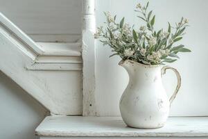 A white vase with some flowers sitting on a wooden step photo