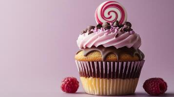 A cupcake with chocolate frosting and a pink lollipop photo