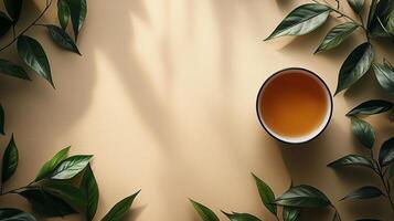 A cup of tea is surrounded by leaves on a beige background photo