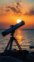 A telescope on a tripod in front of the ocean at sunset photo