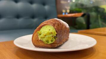round croissant with pistachio green filling in a cafe on the table eat with a fork dessert pastry roll video
