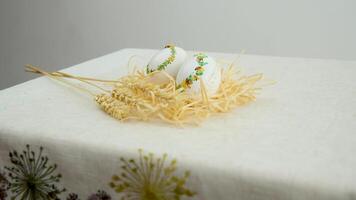 wheat easter eggs two white chicken eggs lie on a wooden table, a small light feather falls on top, against a background of ripe ears of wheat video