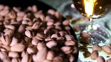 beer with pistachios Slow motion handheld shot of apple cider in glass and pistachios in black bowl on concrete countertop video