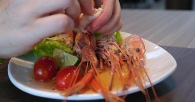 Hands methodically peeling shrimp on a plate video
