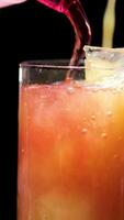 Bartender at the bar prepares a refreshing orange cocktail, a red cocktail with ice cubes and skillfully mixes it with a bar spoon. Close up. Slow motion video