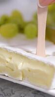 grapes White soft moldy Camembert cheese piece cut with knife close up video
