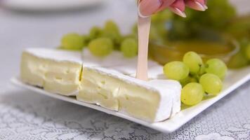 grapes White soft moldy Camembert cheese piece cut with knife close up video