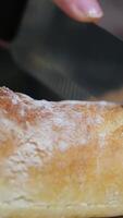 Baguette. French Baguette. Homemade bread loaf being sliced on a cutting board by the chef in a home kitchen. After baking in the oven. Cheese and wine in the background. Action shot. Hands and pans. video