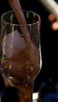 Super slow motion macro of old malt bourbon whiskey is poured in cocktail with ice cubes in transparent glass is being mixed by bartender in bar or club. video