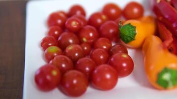 Red bell pepper slowly spins, resting on a plate of vibrant red and yellow cherry tomatoes video