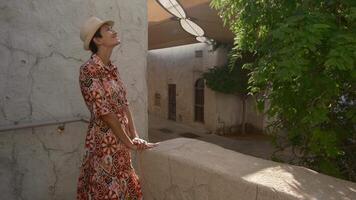 Young woman in ethnic dress and hat exploring Al Seef Park in Dubai. Surrounded by traditional Emirati architecture and modern vibes, she enjoys charm of Dubai cultural heritage, Alseef distrikt. video