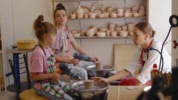 Three people learn pottery techniques at a studio in a creative workshop video