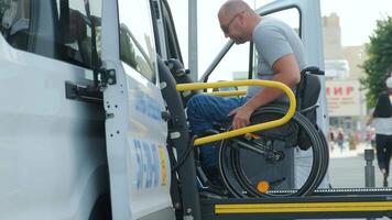 Person in wheelchair rising on hydraulic platform beside open van door. video