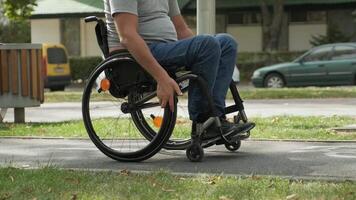 Side view of a wheelchair user pushing forward on a smooth city path. video