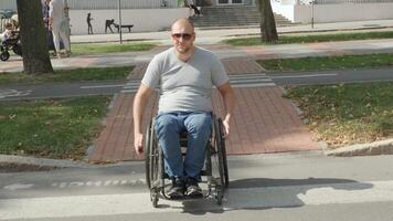 Person with disabilities rolling up from a sidewalk to paved area near crosswalk. video