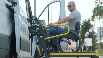 Side view of man using motorized lift to enter accessible minibus. video